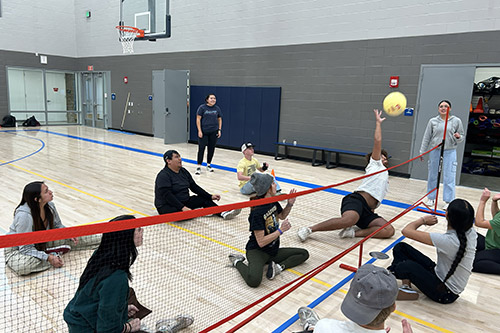 Students playing volleyball sitting down