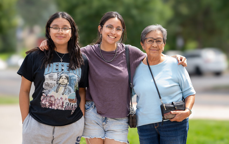 Multigenerational family members posing together in an outdoor campus setting.