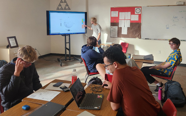 Students in a classroom as one of them is presenting to the others