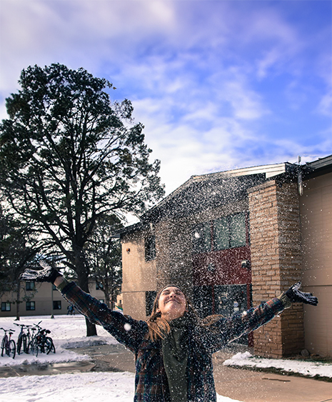 Student playing in the snow outside of campus housing